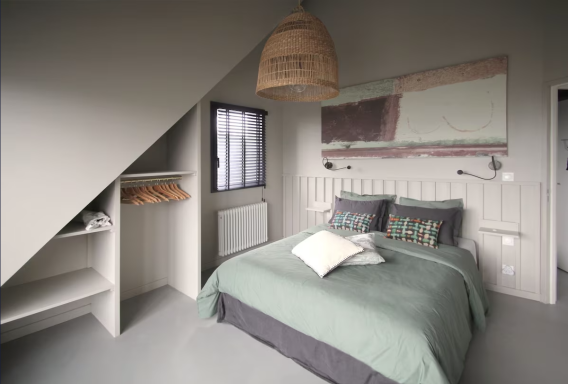 Chambre moderne avec lit double, décoration minimale et murs gris.