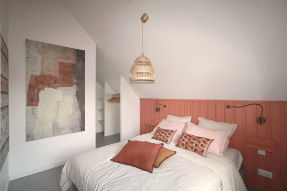 Chambre moderne avec lit double, murs peach et décoration artistique au mur.